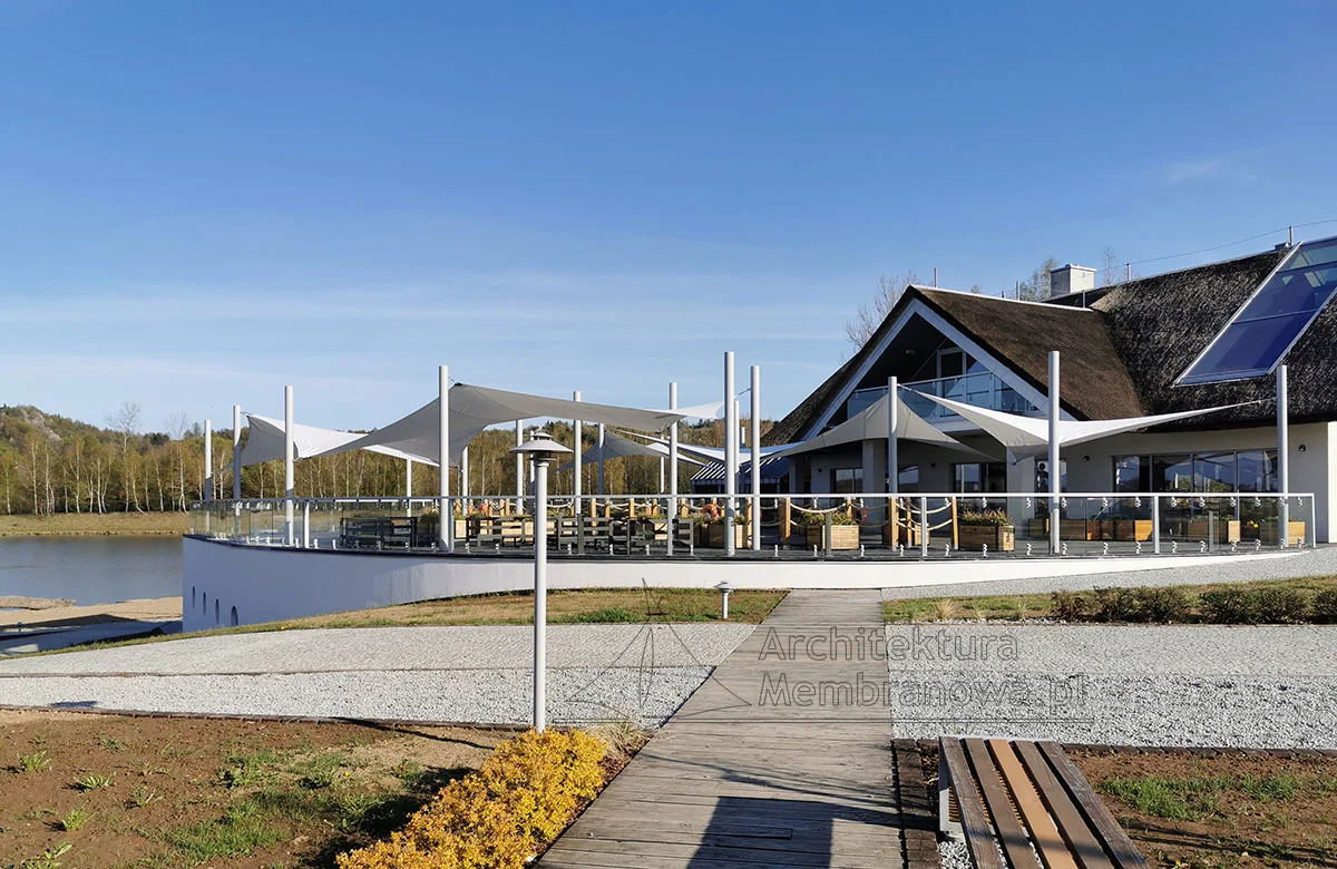 Restauracja nad wodą z membranowym zadaszeniem tarasu i czystym niebem